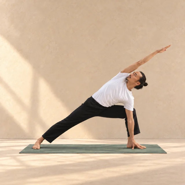 Utthita Parsvakonasana, angle latéral étiré, main au sol et bras opposé allongé au-dessus de la tête dans le studio ASANARC.