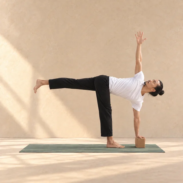 Parivrtta Ardha Chandrasana, demi-lune en torsion, avec main croisée sur un bloc près du pied d’appui et bras opposé levé.