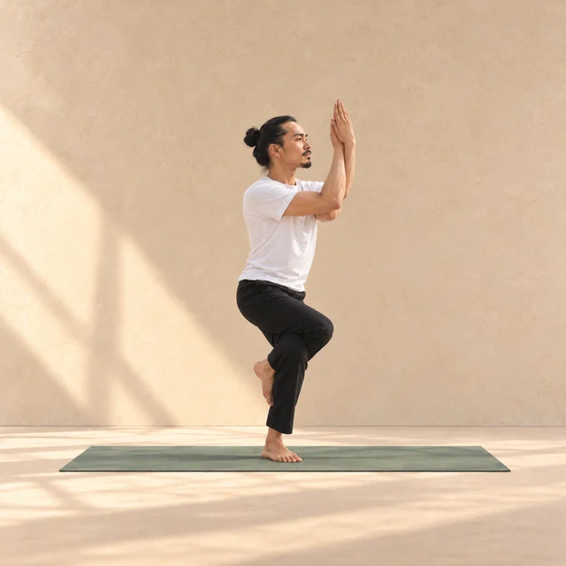 Garudasana : cuisse droite croisée au-dessus de la gauche, pied enroulé derrière le mollet et regard dirigé vers les mains.