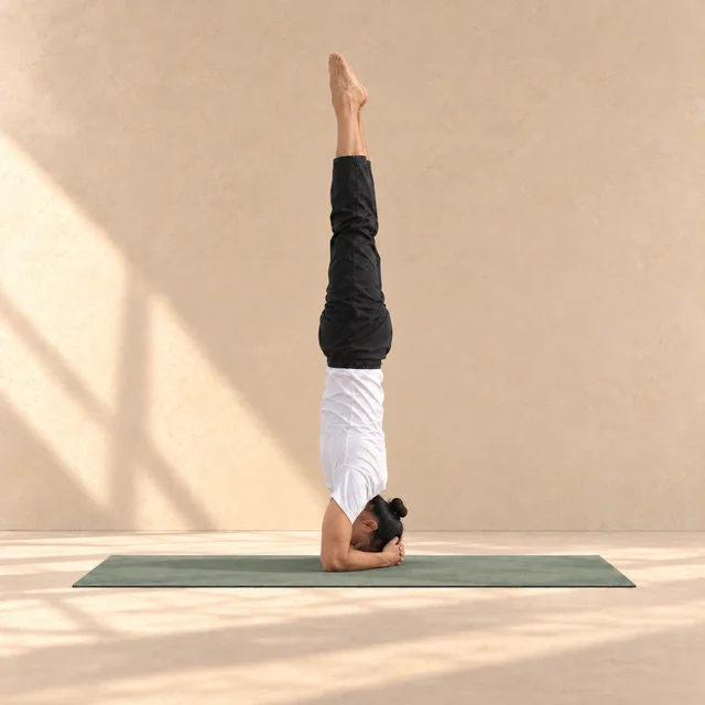 Salamba Sirsasana de profil vers la gauche, tête et avant-bras au sol, jambes verticales et talons derrière les orteils.