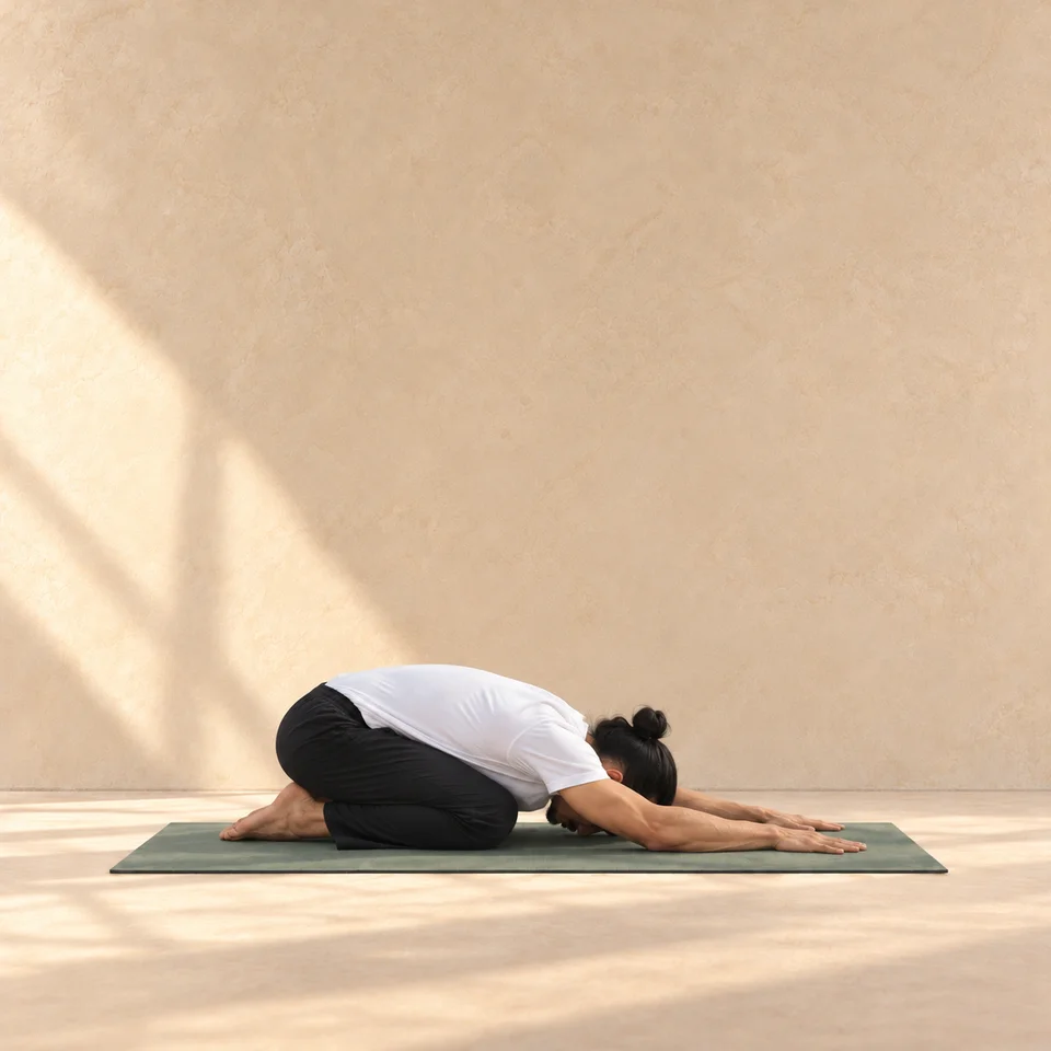 Balasana de profil, tête à droite, bassin vers les talons et bras allongés sur le tapis.