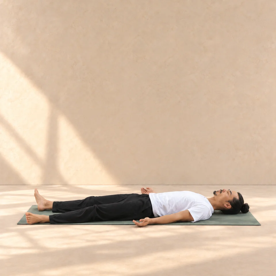 Savasana de profil, tête à droite, allongé sur le dos avec jambes et bras relâchés sur le tapis.