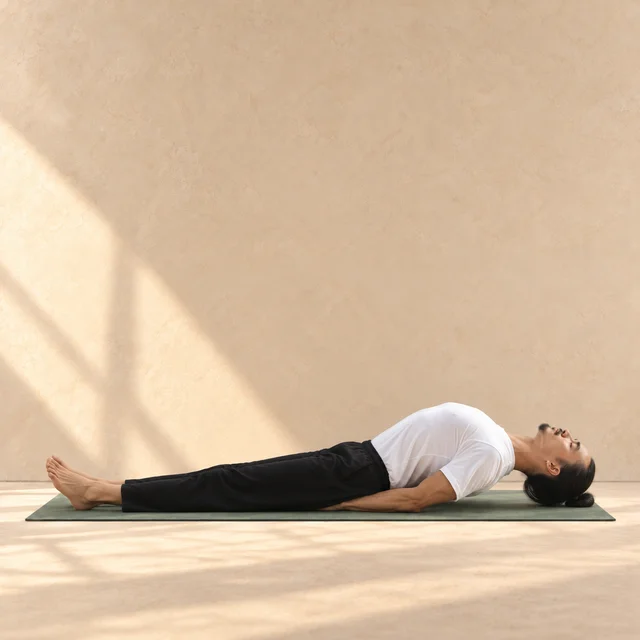 Matsyasana de profil, tête à droite : jambes allongées, poitrine arquée vers le haut, avant-bras en appui et sommet de la tête près du tapis.