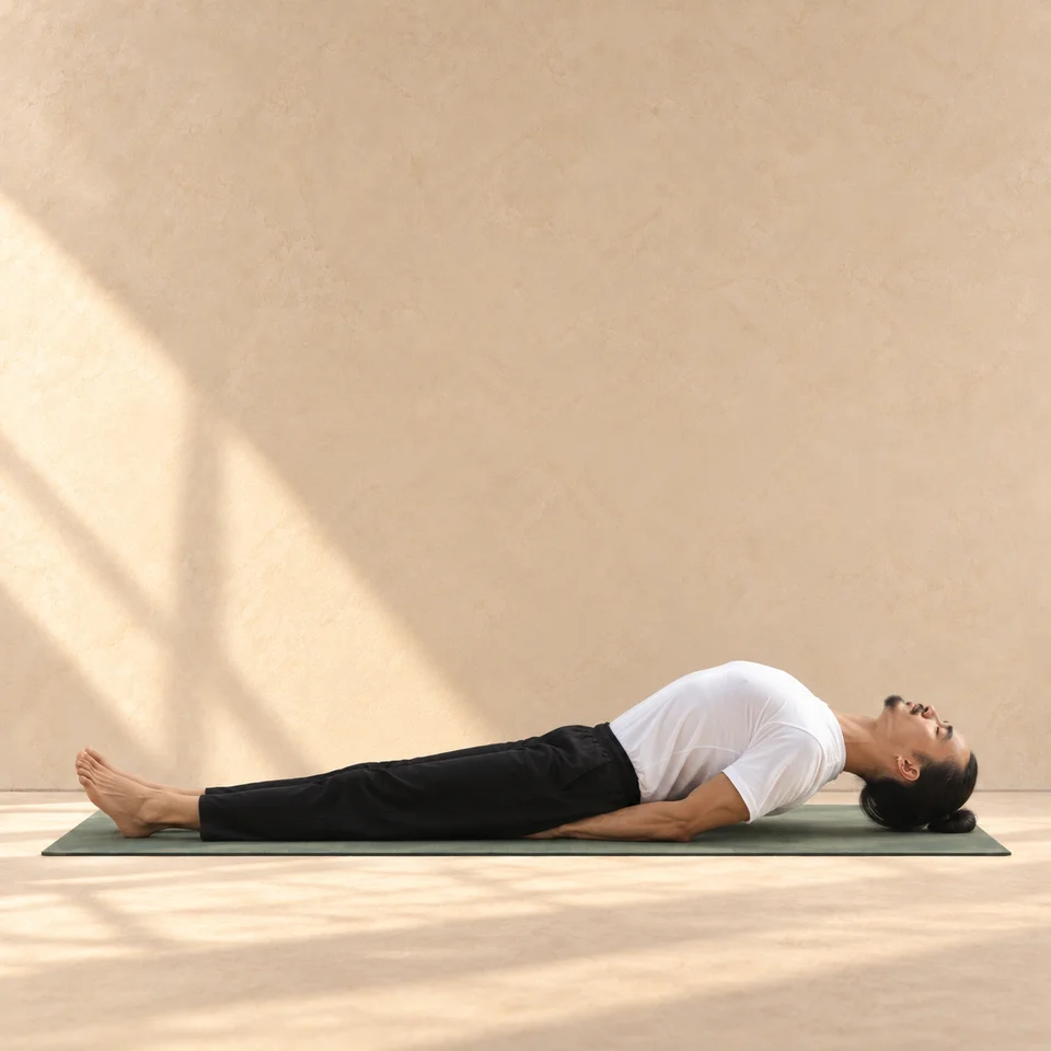 Matsyasana de profil, tête à droite : jambes allongées, poitrine arquée vers le haut, avant-bras en appui et sommet de la tête près du tapis.