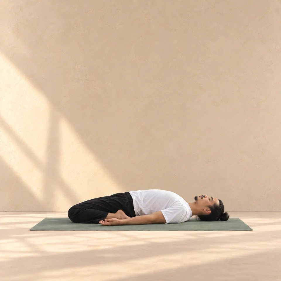 Supta Virasana de profil : homme allongé sur le dos, deux genoux repliés en posture du héros, pieds près du bassin et bras au sol.